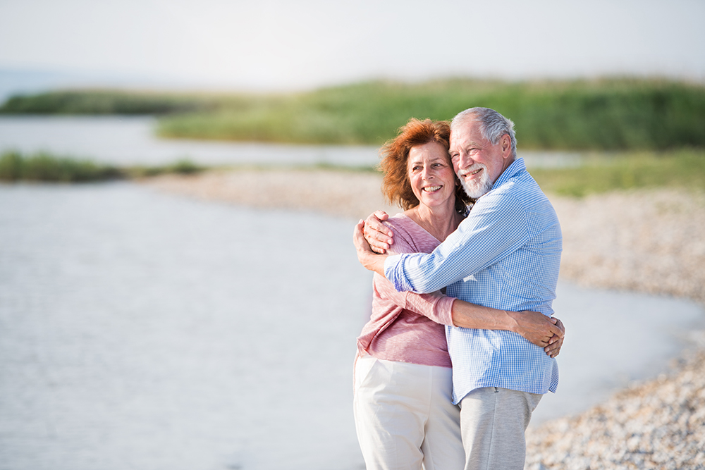 Senior couple hugging by a lake