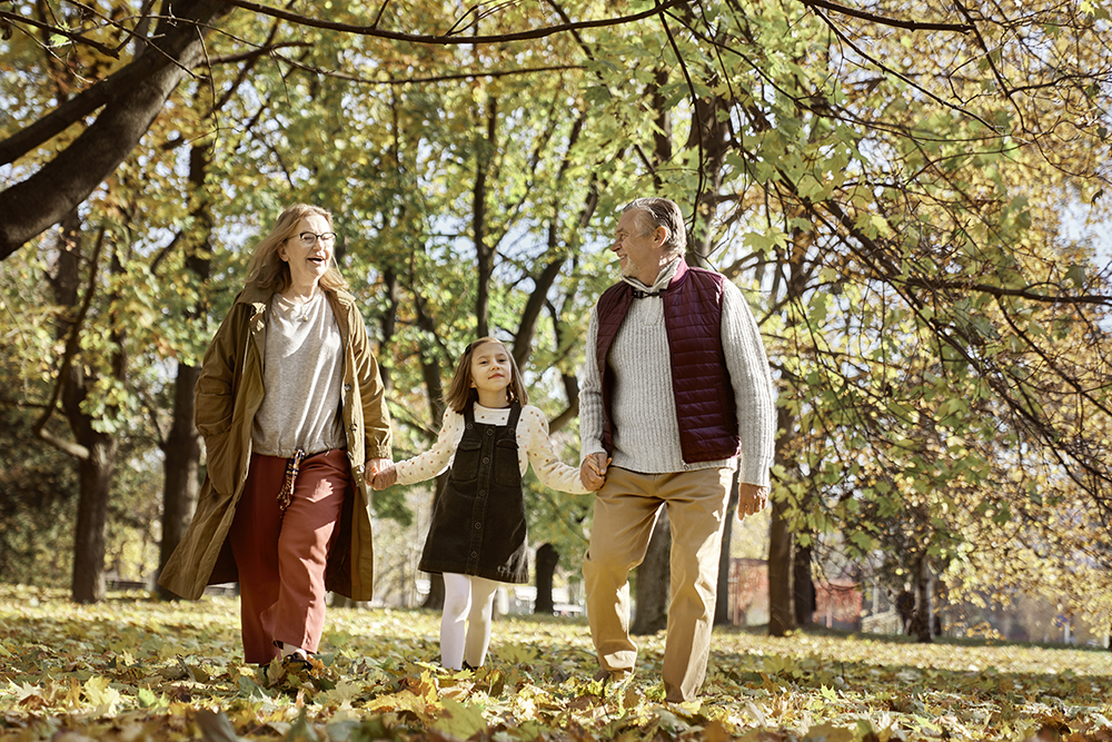 Senior couple walking with a child in autumn